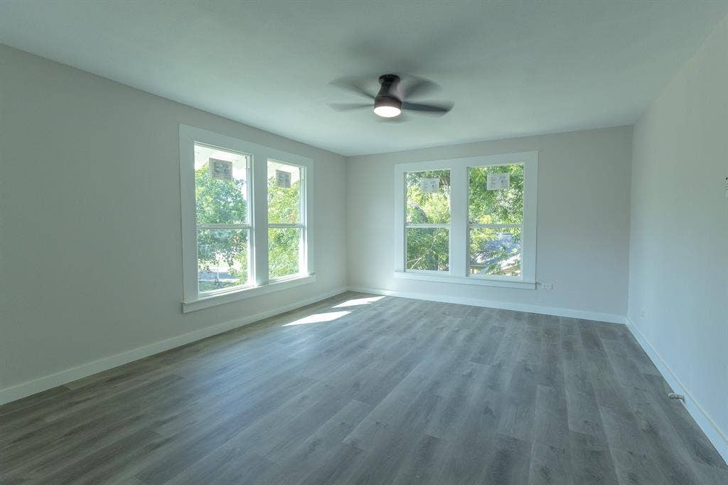 1702 Ethel Avenue, Waco, TX 76707 Expansive room featuring wood-finish flooring, a ceiling fan, and multiple windows with white trim