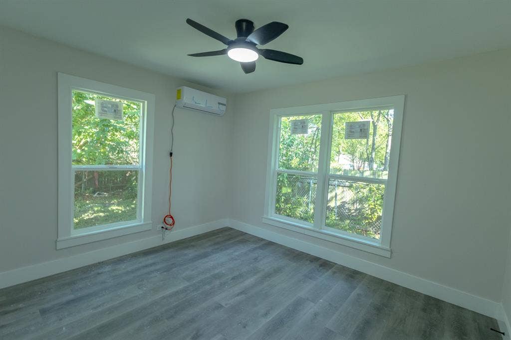 1702 Ethel Avenue, Waco, TX 76707 Contemporary ceiling fan with integrated lighting, wood-finish flooring, multiple windows, and a wall-mounted air conditioning unit