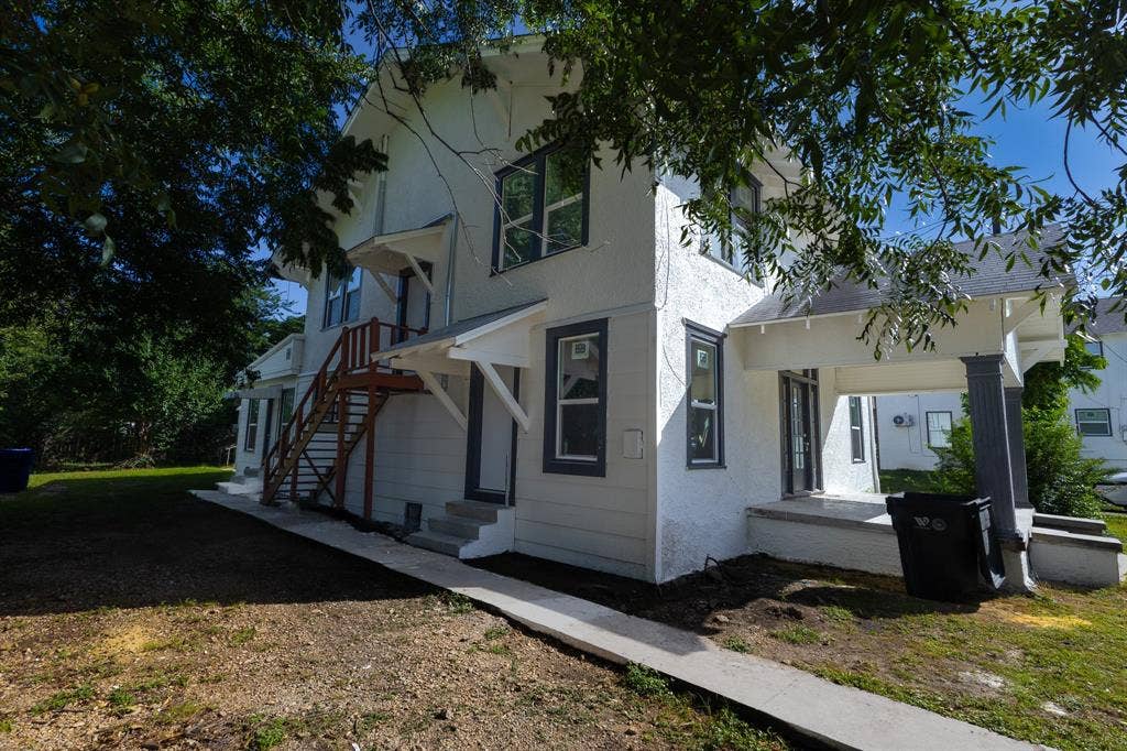 1702 Ethel Avenue, Waco, TX 76707 Classic two-story home featuring white horizontal siding, multi-pane windows, and a covered entry with wooden staircase
