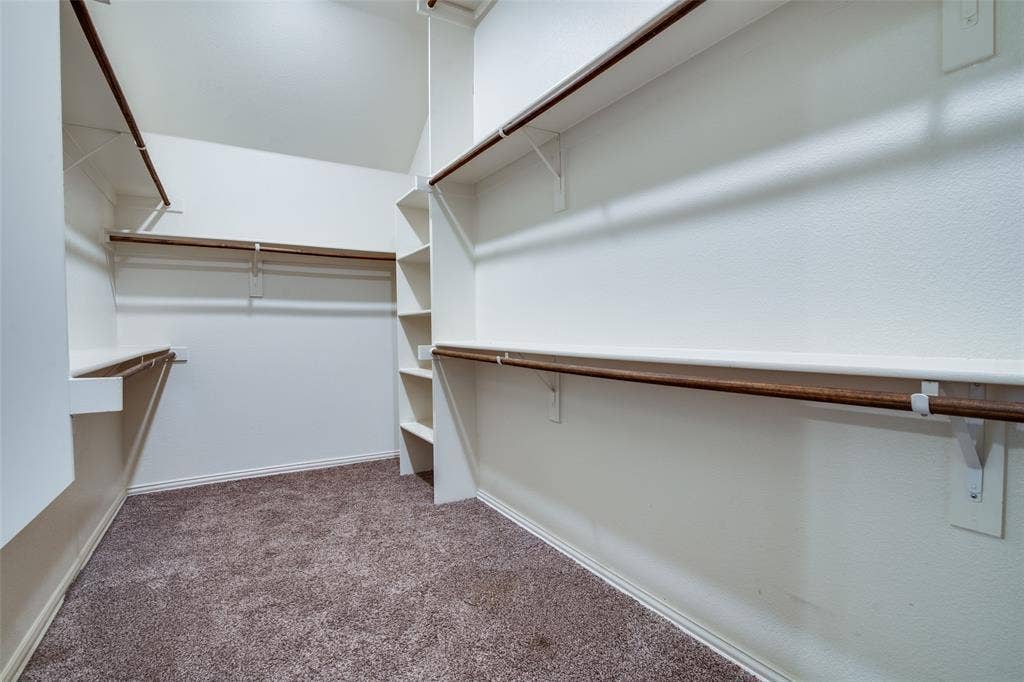 1813 Chadwick Lane, Forney, TX 75126 Spacious walk-in closet featuring multiple shelving units, varied hanging rods, and neutral-toned carpeting