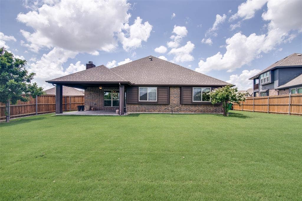 1813 Chadwick Lane, Forney, TX 75126 Expansive backyard featuring a manicured lawn, full privacy fencing, and a covered patio