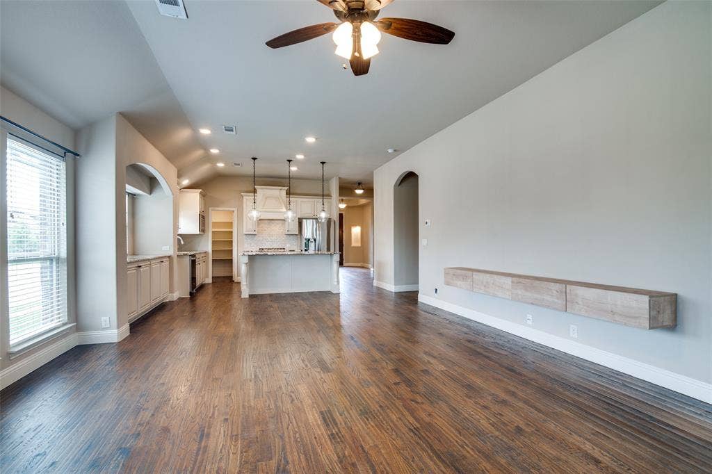 1813 Chadwick Lane, Forney, TX 75126 Open-concept living area showcasing rich wood-finish flooring, recessed lighting, and a ceiling fan with integrated light fixture