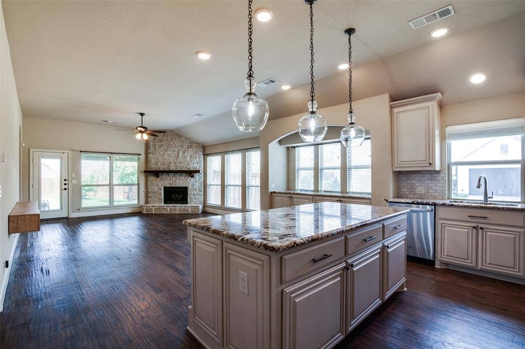 1813 Chadwick Lane, Forney, TX 75126 Wood-finish flooring throughout, a stone fireplace, recessed lighting, and a kitchen island with pendant lighting