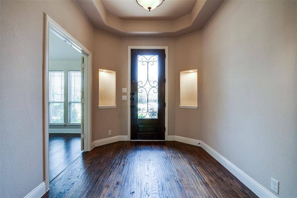 1813 Chadwick Lane, Forney, TX 75126 Entryway featuring wood-finish flooring, a decorative glass-paneled entry door, recessed wall niches, crown molding, and a tray ceiling