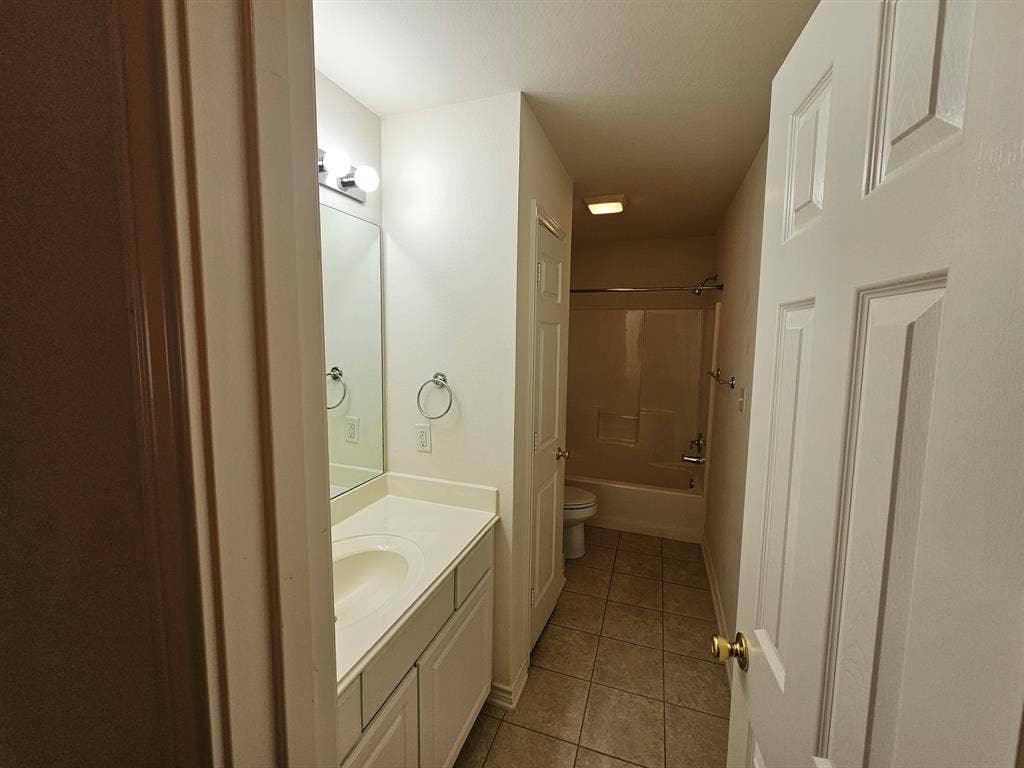 1521 Rice Road, #Z-101, Tyler, TX 75703 White paneled vanity with an integrated sink, polished chrome hardware, and a framed mirror