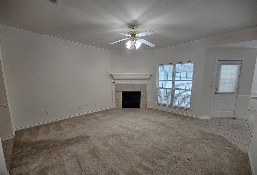 1521 Rice Road, #Z-101, Tyler, TX 75703 Spacious living area featuring a fireplace with a tile surround and mantel, a ceiling fan with integrated lighting, and multiple windows