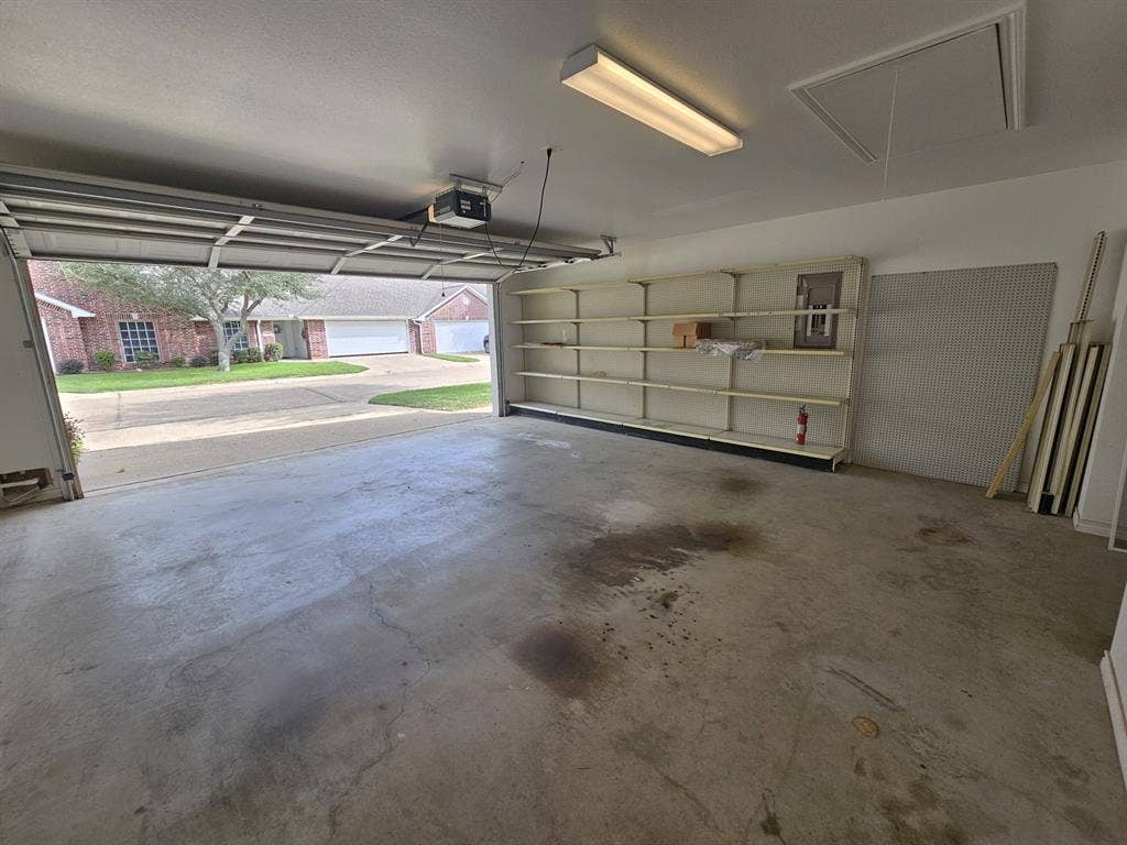 1521 Rice Road, #Z-101, Tyler, TX 75703 Attached garage with a concrete floor, built-in shelving, and white paneled garage door