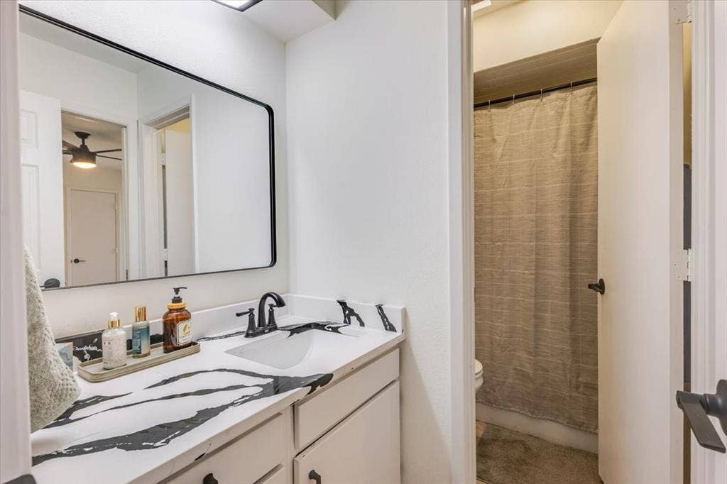 Vanity with a black and white patterned countertop, undermount sink, and matte black faucet