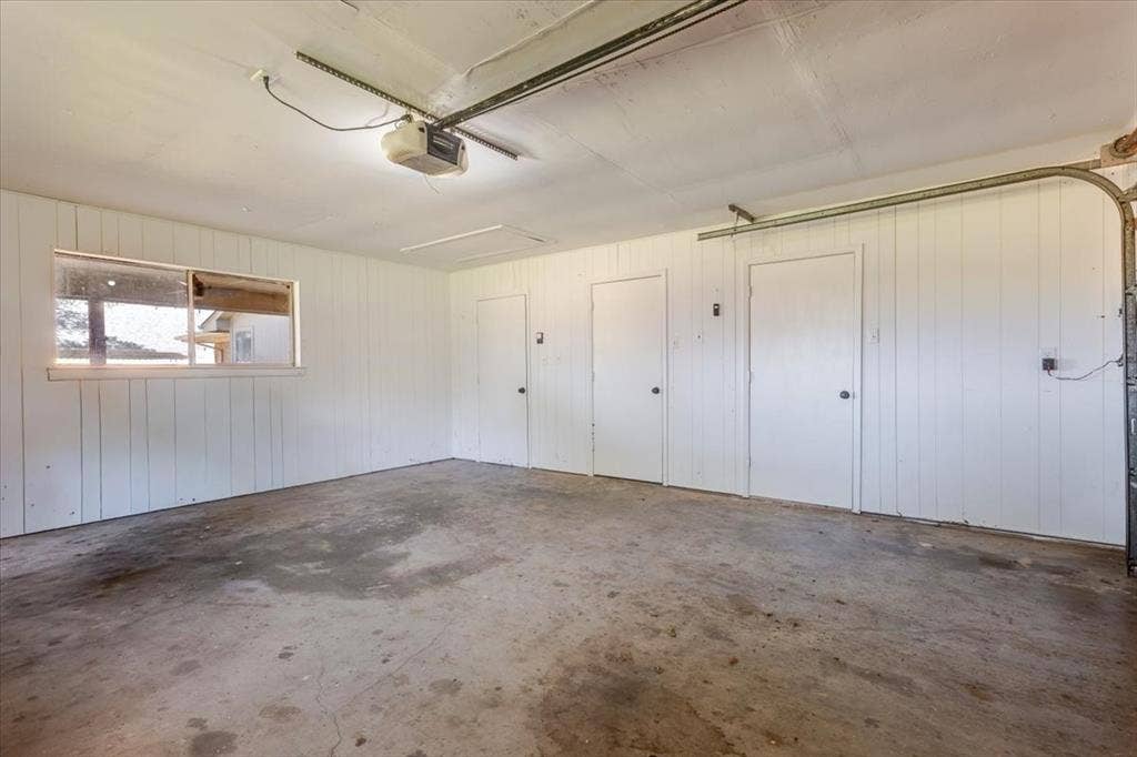 Interior garage space featuring a concrete floor, painted vertical paneling, and an exposed garage door track