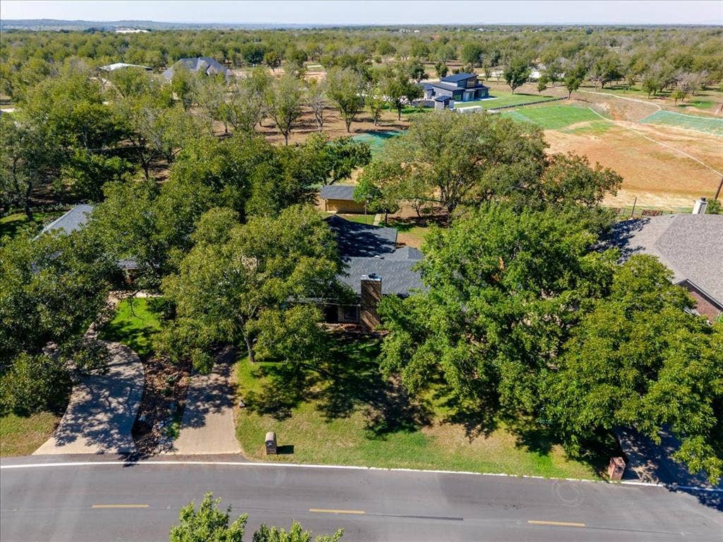 Property features a classic pitched roof, an attached garage, mature trees, and a concrete driveway