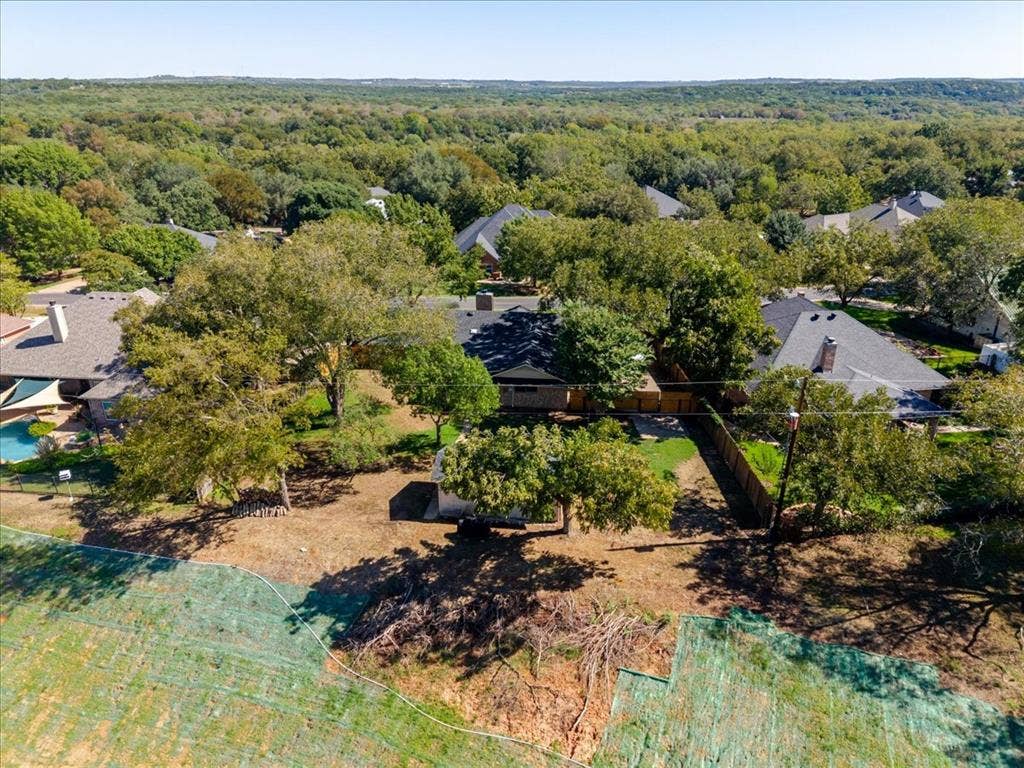 Expansive property with mature trees, a fenced perimeter, and a contemporary-style home featuring a dark roof