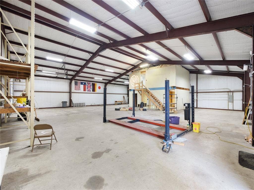 2944 CR-596, Nevada, TX 75173 Spacious open warehouse structure with exposed metal beams, concrete flooring, and an integrated loft with wood stairs