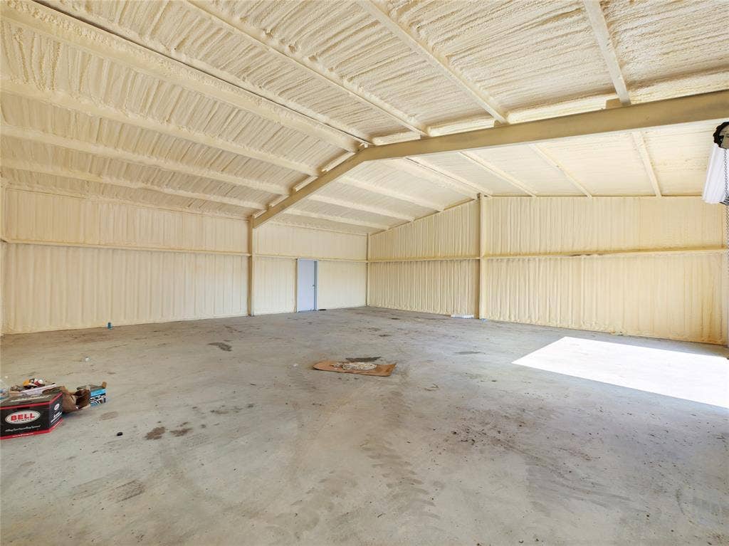2944 CR-596, Nevada, TX 75173 Open warehouse space with concrete flooring, exposed metal beam construction, and spray foam insulation on walls and ceiling