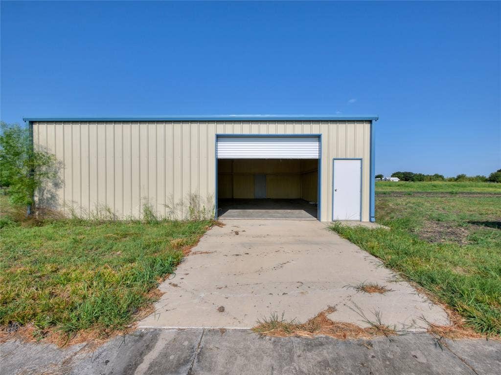 2944 CR-596, Nevada, TX 75173 Metal building with a roll-up door, pedestrian entry door, and concrete drive