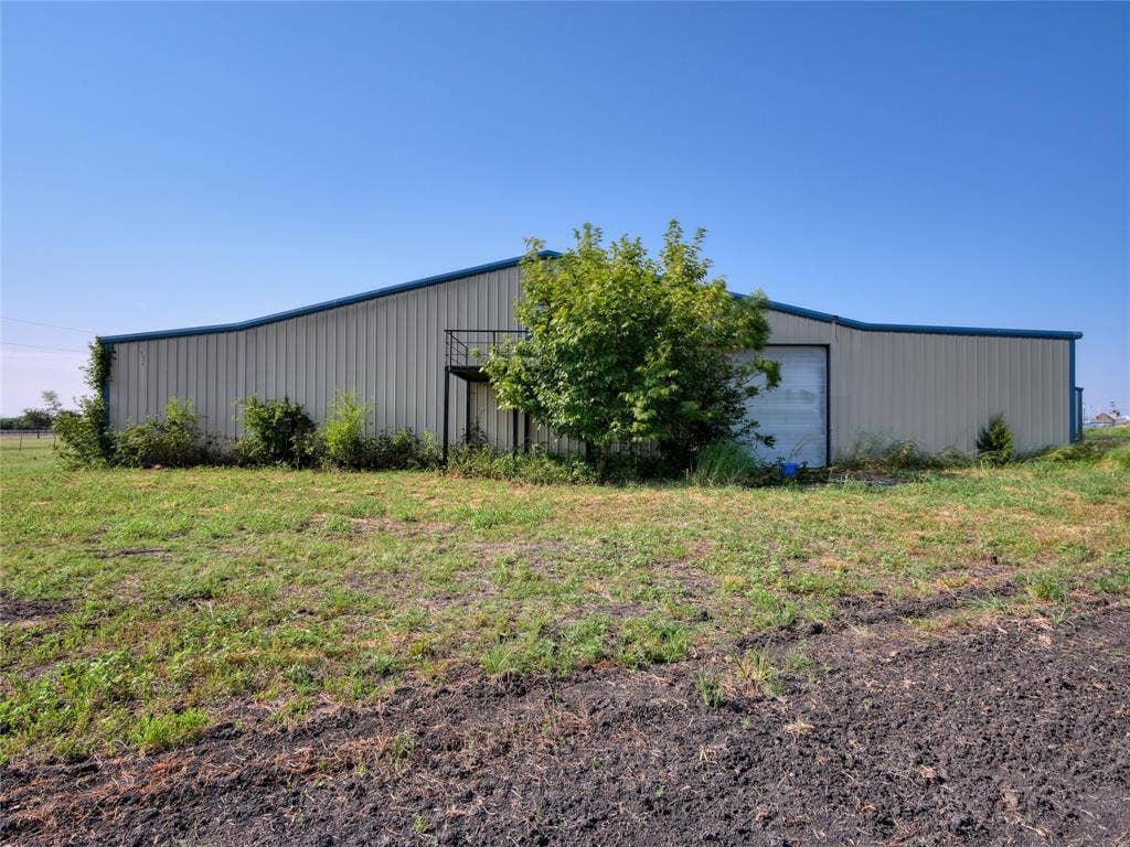 2944 CR-596, Nevada, TX 75173 Metal building with a blue trim roofline, an exterior staircase, and a large roll-up door