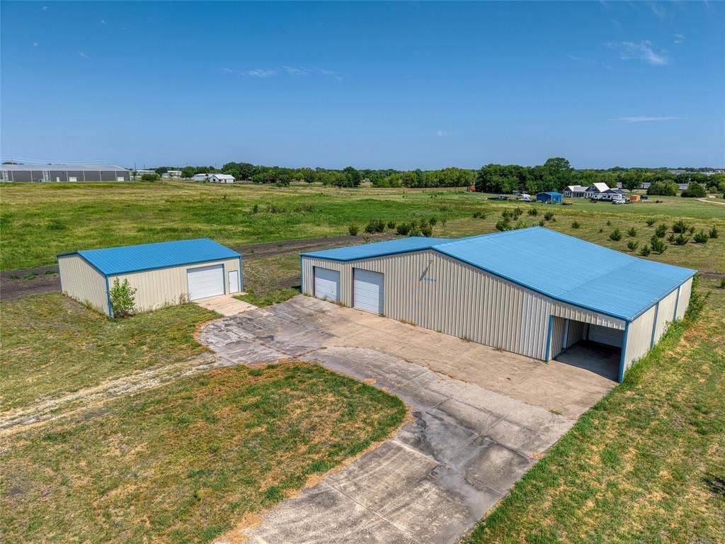 2944 CR-596, Nevada, TX 75173 Two metal buildings with blue roofs, multiple garage doors, and a concrete driveway