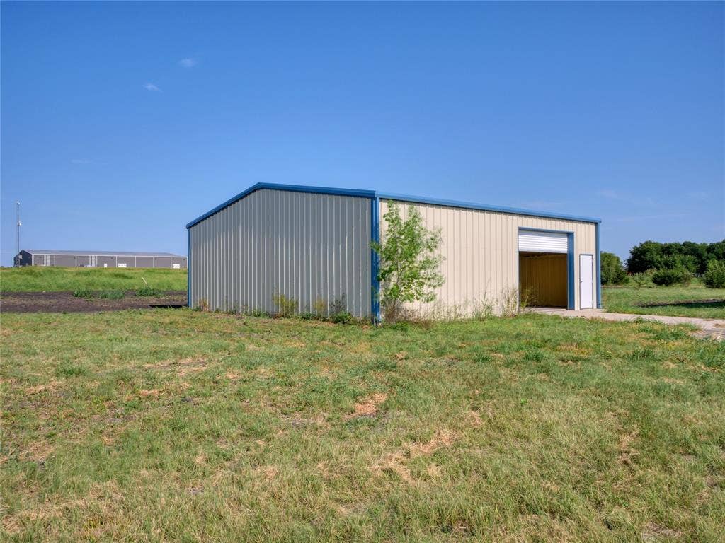 2944 CR-596, Nevada, TX 75173 Metal building featuring a roll-up garage door and an entry door