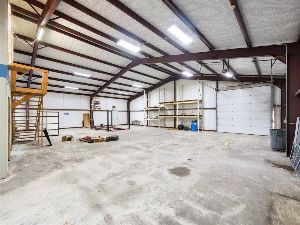 2944 CR-596, Nevada, TX 75173 Concrete flooring, exposed metal beam construction, high ceilings, multiple overhead light fixtures, and a large roll-up door