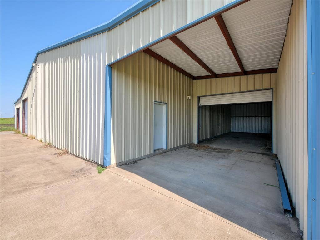 2944 CR-596, Nevada, TX 75173 Corrugated metal siding with blue trim, concrete drive, and an overhead roll-up door