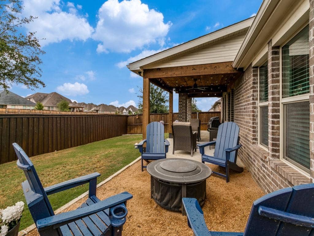5513 Baker Creek Road, Fort Worth, TX 76126 Backyard features a covered patio, brick exterior, and a manicured lawn