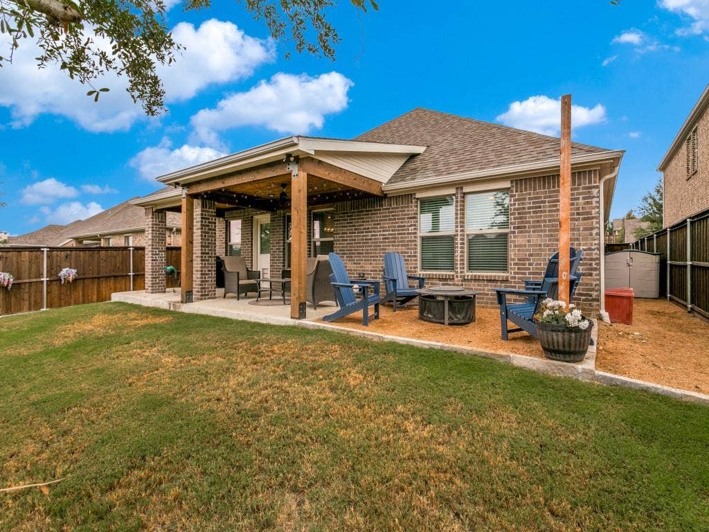 5513 Baker Creek Road, Fort Worth, TX 76126 Expansive backyard featuring a covered patio with string lighting, brick exterior, and a gravel seating area