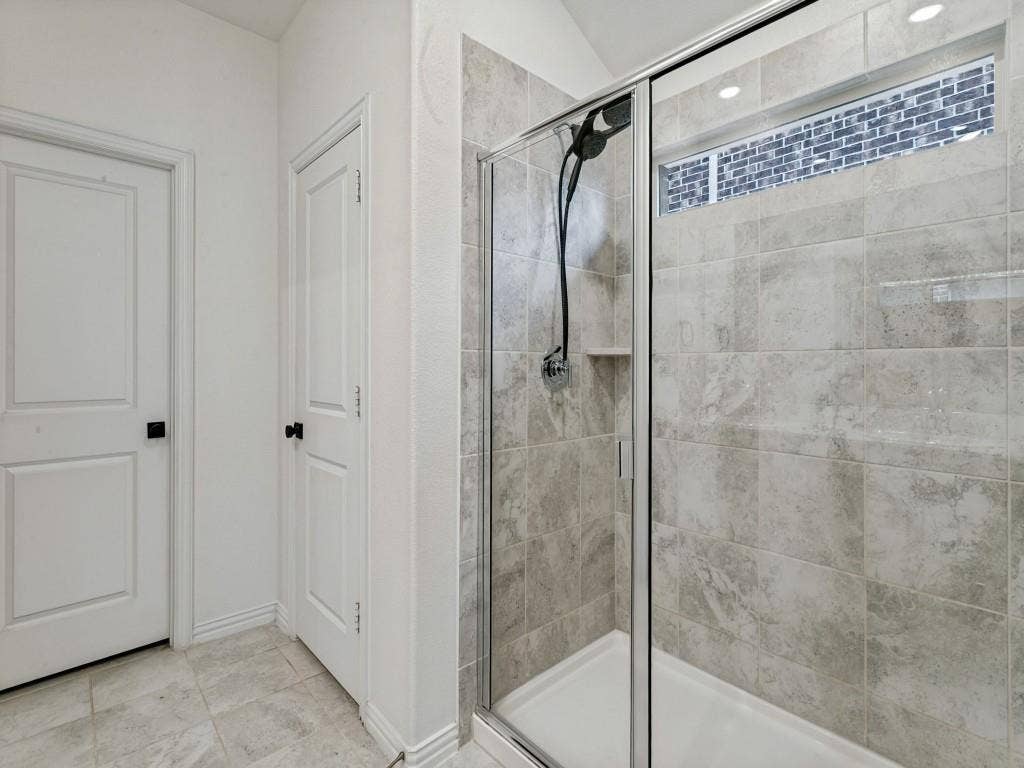 5513 Baker Creek Road, Fort Worth, TX 76126 Glass-enclosed shower with a built-in niche and a dark-finish shower system