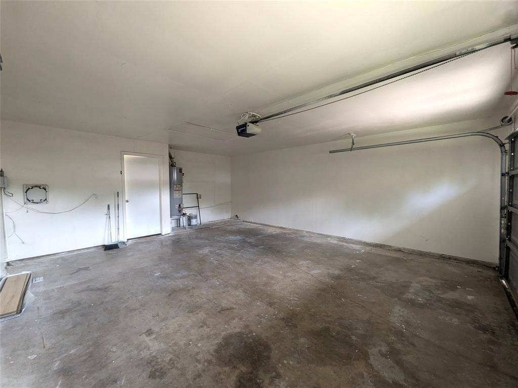 1400 Oakhill Drive, Plano, TX 75075 Spacious garage with an overhead door opener, concrete flooring, and a white interior door
