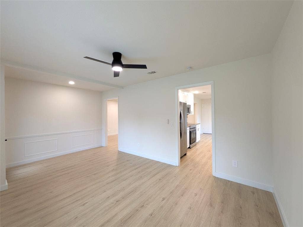 1400 Oakhill Drive, Plano, TX 75075 Open-concept living area with wood-finish flooring, white walls, and a contemporary ceiling fan