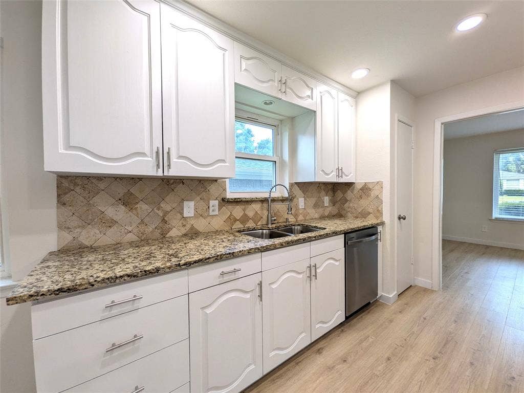 1400 Oakhill Drive, Plano, TX 75075 Kitchen featuring white cabinetry, granite countertops, a stainless steel sink, a tile backsplash, and light wood-finish flooring
