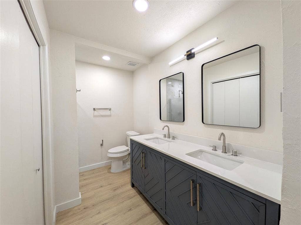 1400 Oakhill Drive, Plano, TX 75075 Bathroom featuring a double vanity with dark blue cabinetry, white countertops, and dual undermount sinks