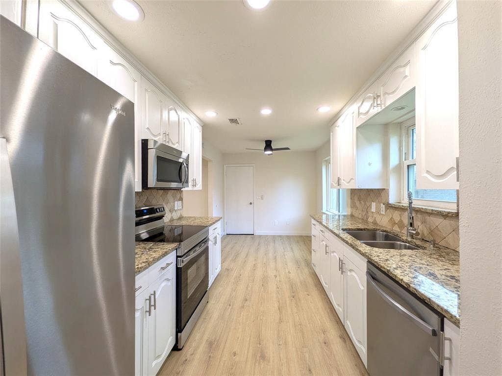 1400 Oakhill Drive, Plano, TX 75075 Updated kitchen featuring white cabinetry, stone countertops, stainless steel appliances, recessed lighting, and wood-finish flooring