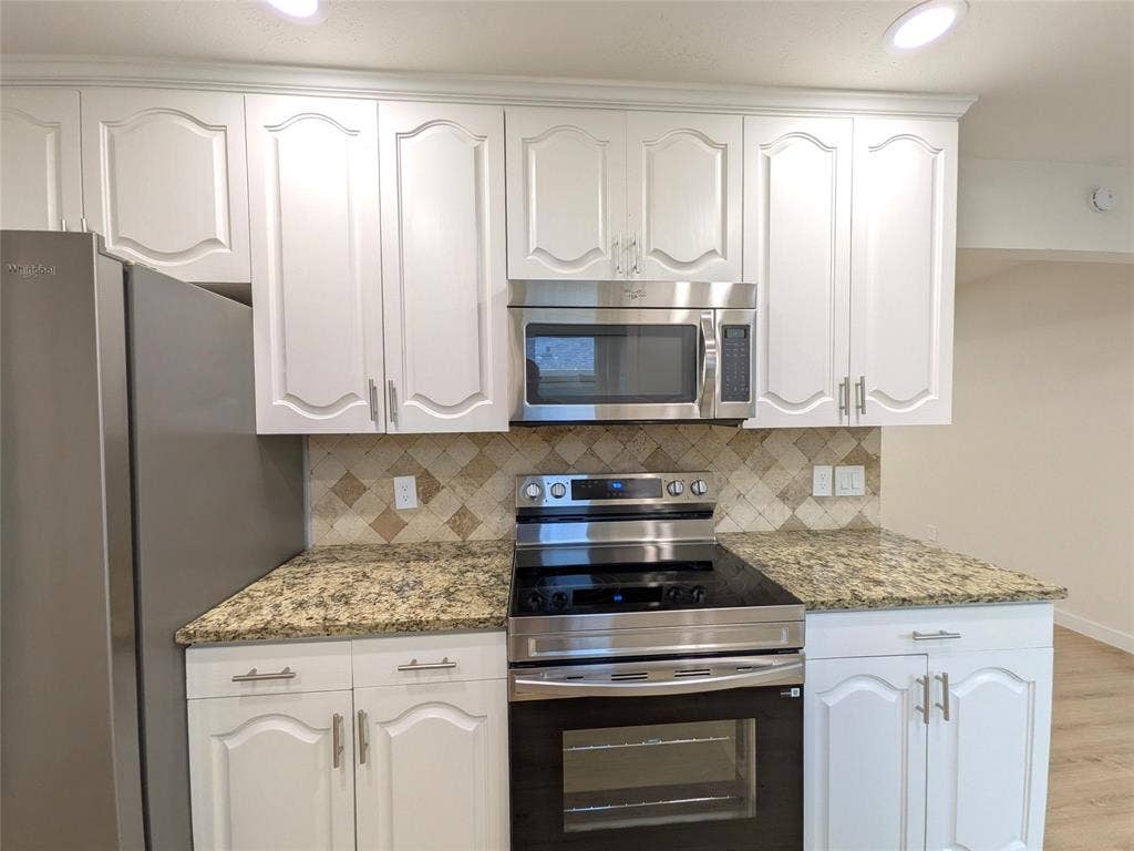 1400 Oakhill Drive, Plano, TX 75075 Kitchen featuring white cabinetry with brushed nickel hardware, stainless steel appliances, granite countertops, and a mosaic tile backsplash