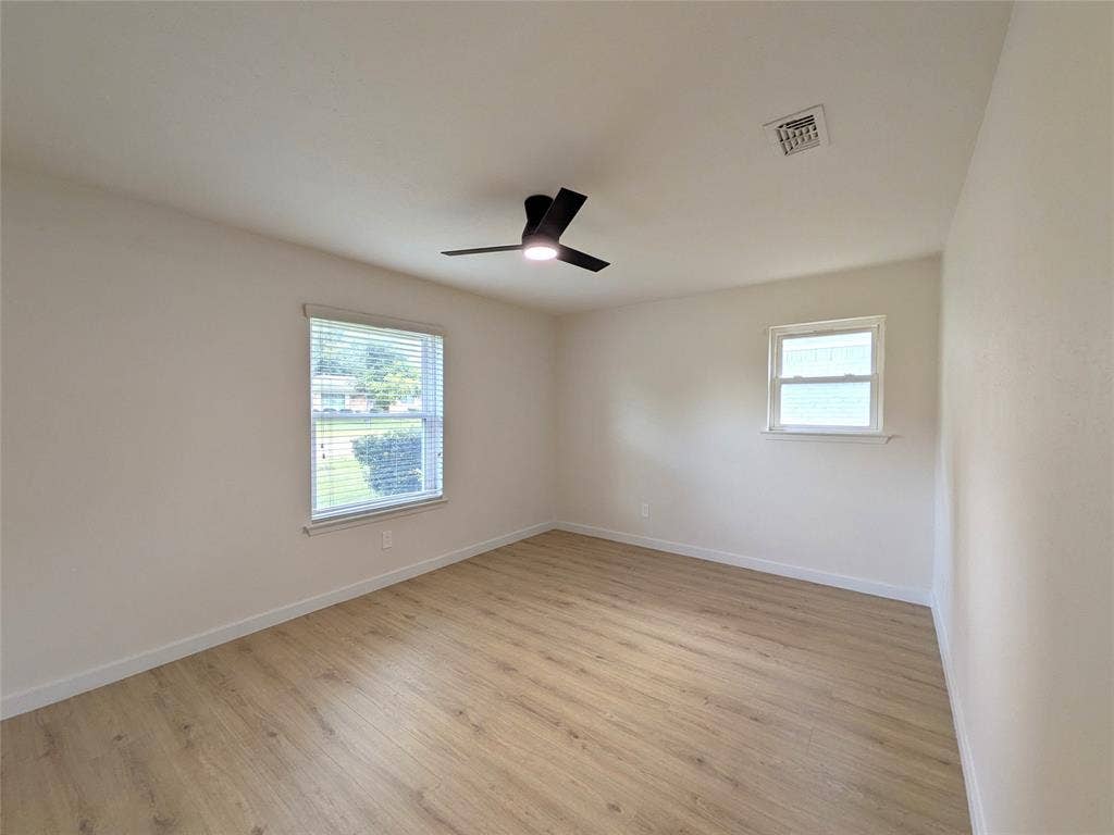 1400 Oakhill Drive, Plano, TX 75075 Room with wood-finish flooring, two windows with blinds, a black ceiling fan with integrated lighting, and white baseboards