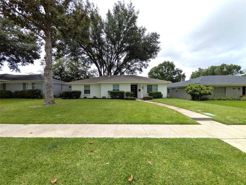 1400 Oakhill Drive, Plano, TX 75075 Single-story residence featuring a white brick exterior, dark entry door, and a light-colored roof