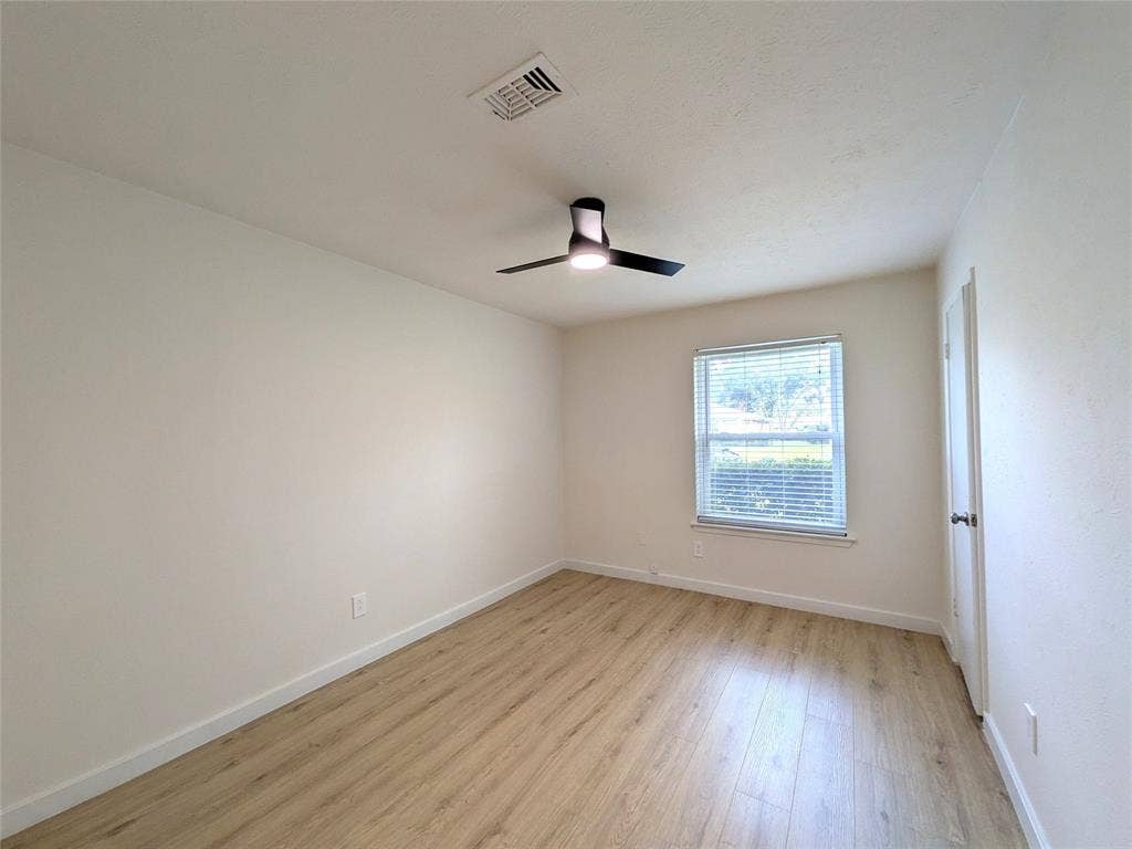1400 Oakhill Drive, Plano, TX 75075 Bright interior space featuring wood-finish flooring, a modern ceiling fan with integrated lighting, and a single window with horizontal blinds