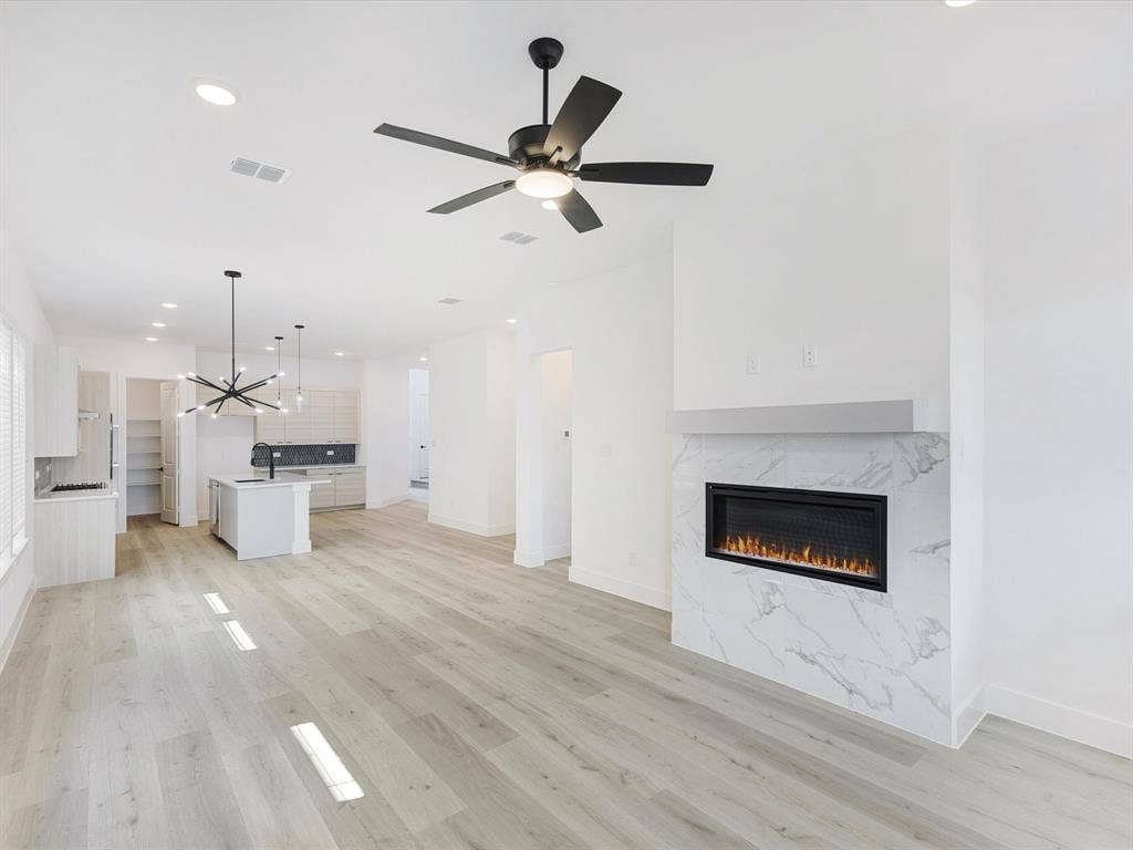 2317 Peters Colony Drive, Little Elm, TX 75036 Unfurnished living room with recessed lighting, light wood-style flooring, a high end fireplace, a chandelier, and ceiling fan
