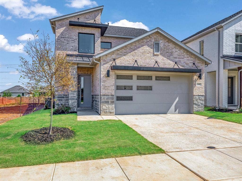 2317 Peters Colony Drive, Little Elm, TX 75036 View of front of property featuring brick siding, a garage, concrete driveway, and stone siding