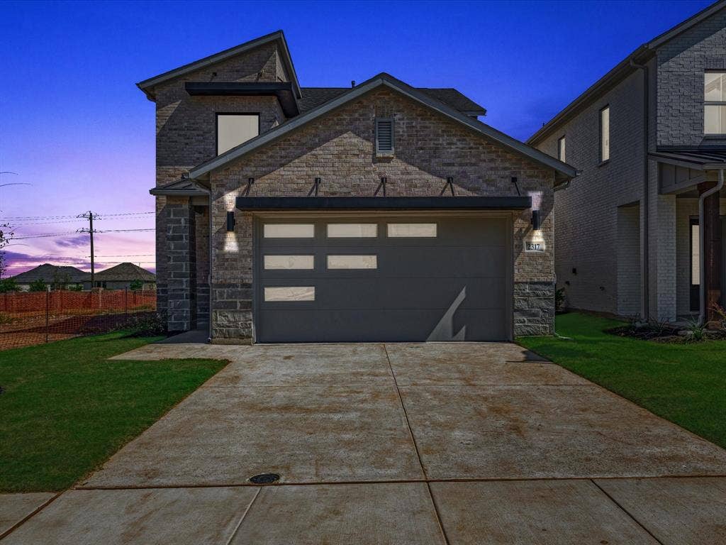 2317 Peters Colony Drive, Little Elm, TX 75036 View of front of property featuring stone siding, a garage, a front lawn, and driveway