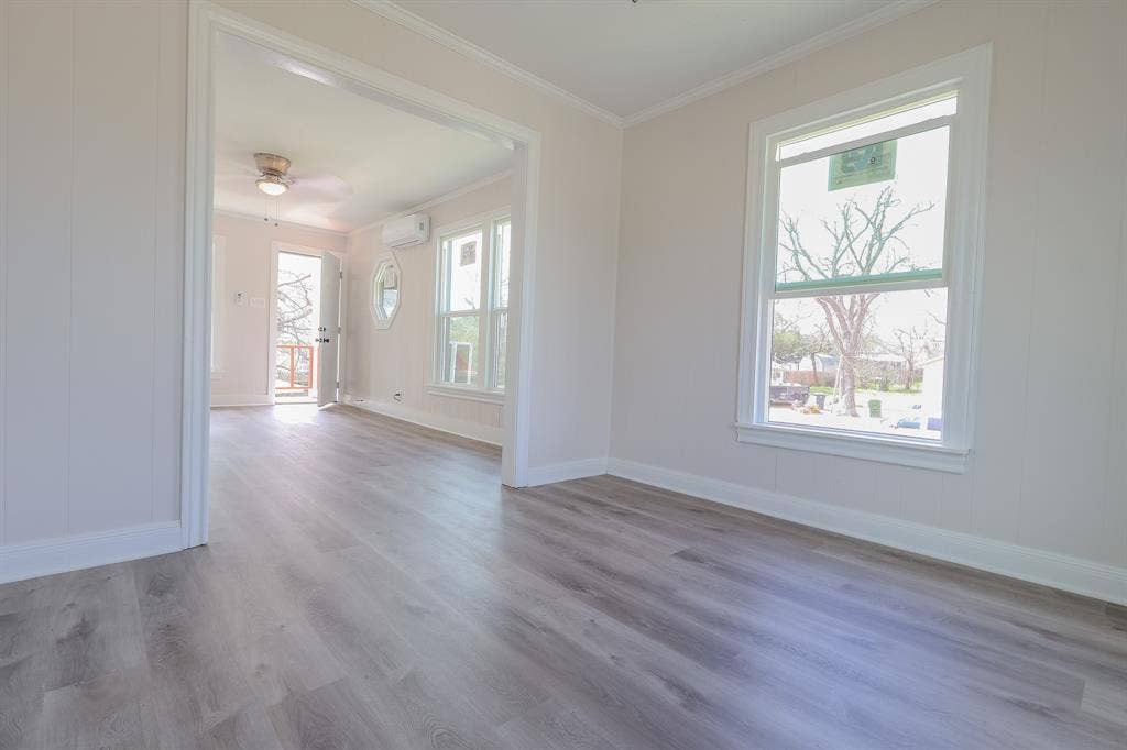 1704 Ethel Avenue, #B, Waco, TX 76707 Wood-finish flooring throughout, white wall paneling, and an open doorway to an additional room