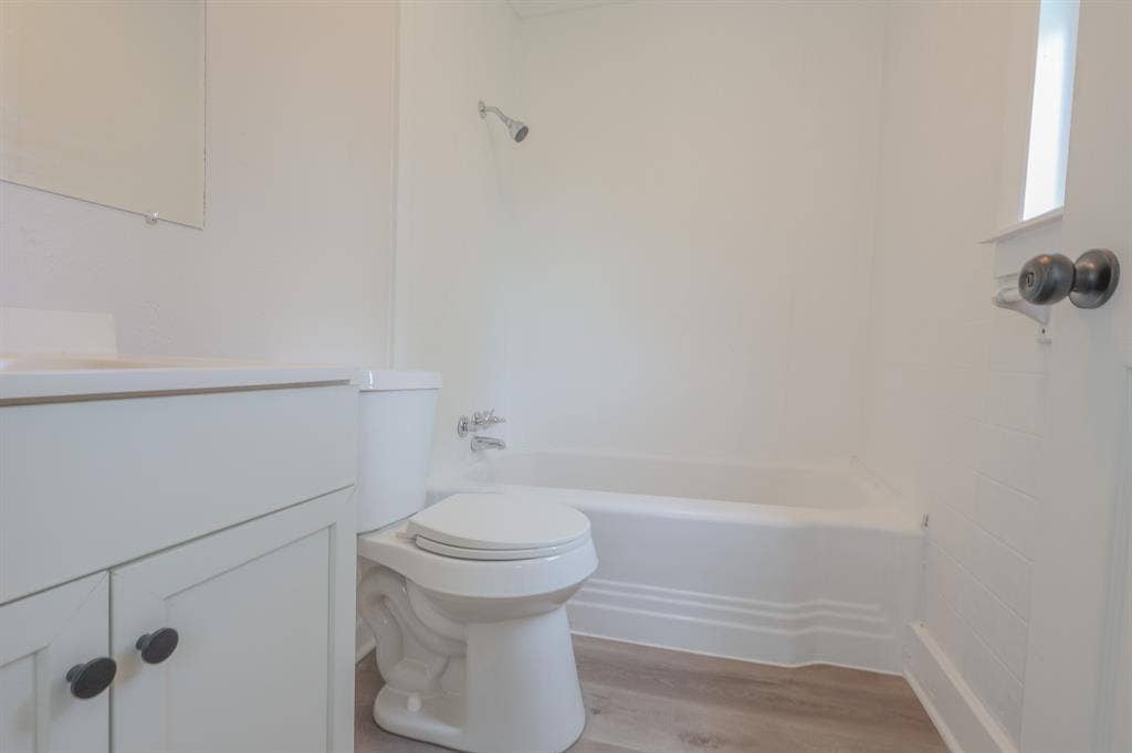 1704 Ethel Avenue, #B, Waco, TX 76707 Bathroom featuring a built-in tub and shower combination, vanity with cabinet storage, and wood-finish flooring