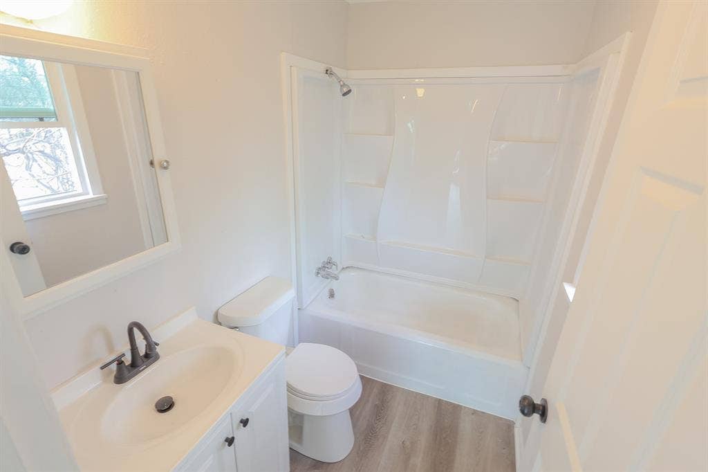 1704 Ethel Avenue, #B, Waco, TX 76707 White vanity with an integrated sink and dark bronze faucet, framed mirror, and a window