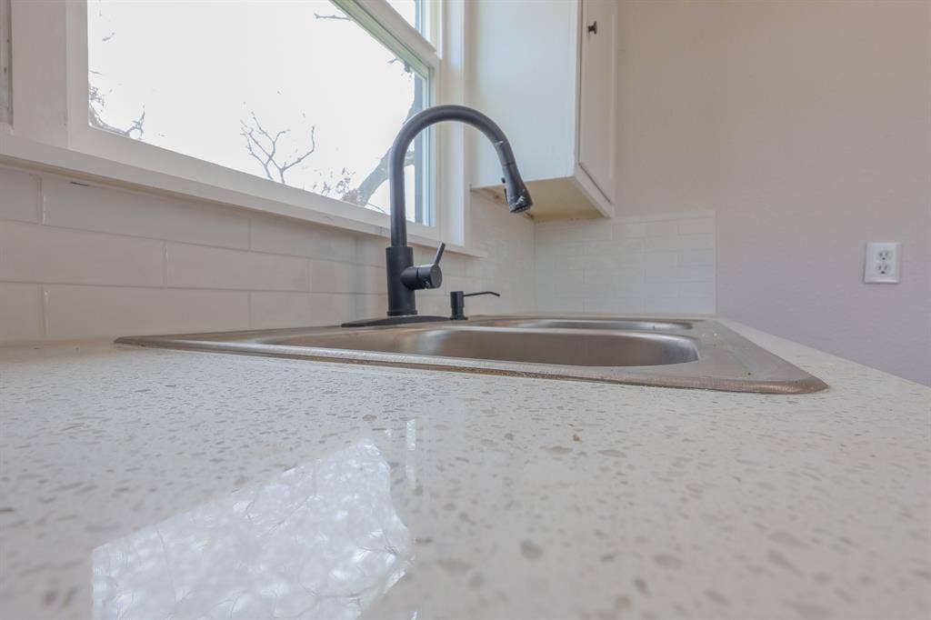1704 Ethel Avenue, #B, Waco, TX 76707 Dual-basin stainless steel sink with a matte black high-arc faucet, set within a speckled white countertop