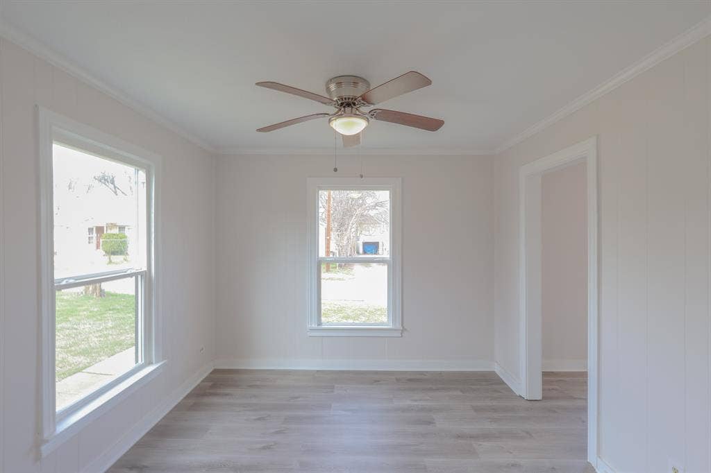 1704 Ethel Avenue, #B, Waco, TX 76707 Ceiling fan with integrated lighting, wood-finish flooring, two double-hung windows, and a doorway with white trim