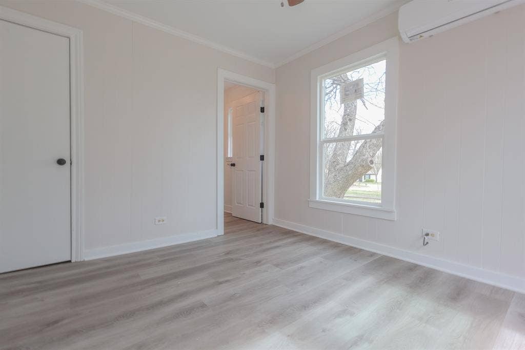 1704 Ethel Avenue, #B, Waco, TX 76707 Wood-finish flooring with white trim, a double-hung window, and a wall-mounted mini-split unit