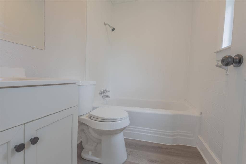 1704 Ethel Avenue, #B, Waco, TX 76707 White vanity with dark hardware, a toilet, and a white bathtub with a shower head