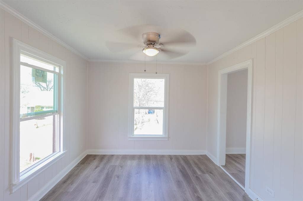 1704 Ethel Avenue, #B, Waco, TX 76707 Wood-finish flooring, two large windows, white wall paneling, crown molding, and a ceiling fan with integrated lighting