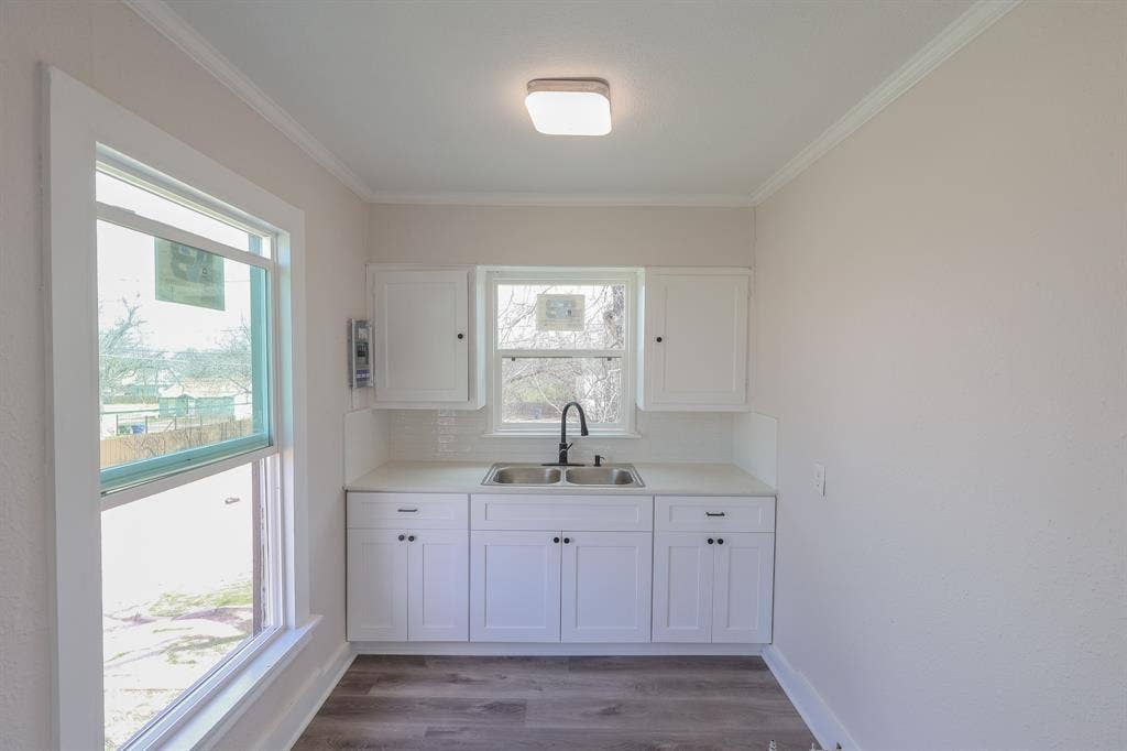 1704 Ethel Avenue, #B, Waco, TX 76707 White shaker-style cabinetry with matte black hardware, dual basin stainless steel sink with matte black faucet, light-toned countertop, and white subway tile backsplash