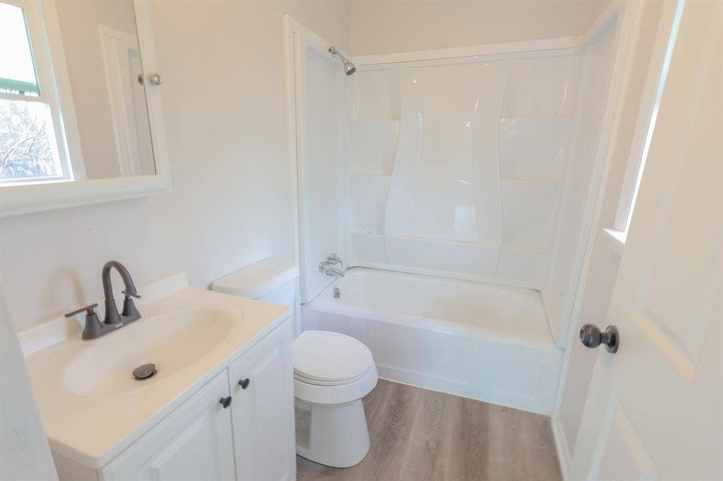 1704 Ethel Avenue, #B, Waco, TX 76707 Contemporary bathroom featuring a white vanity with integrated sink, dark bronze-finish faucet, and a white bathtub with shower