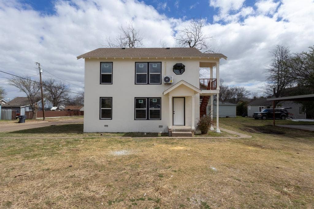1704 Ethel Avenue, #B, Waco, TX 76707 Two-story stucco exterior featuring black-trimmed windows, a ground-level porch with support columns, and an upper-level balcony with a red railing