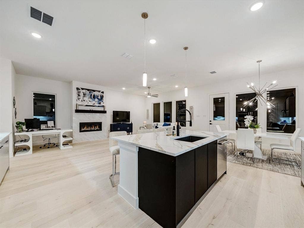 2313 Peters Colony Drive, Little Elm, TX 75036 Kitchen featuring pendant lighting, light wood-type flooring, a premium fireplace, open floor plan, and ceiling fan